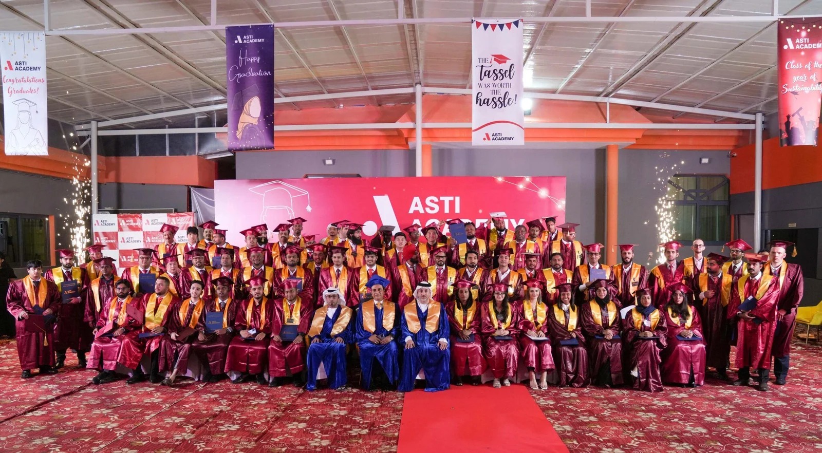 ASTI Academy graduates in gowns at a graduation ceremony